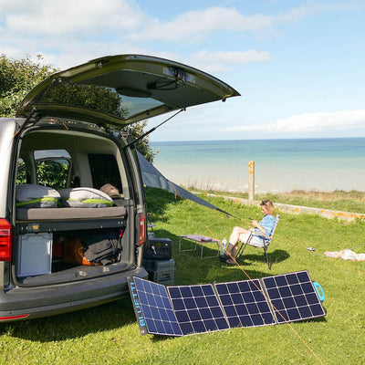 Ein Minicamper steht mit Solaranlage am Meer.