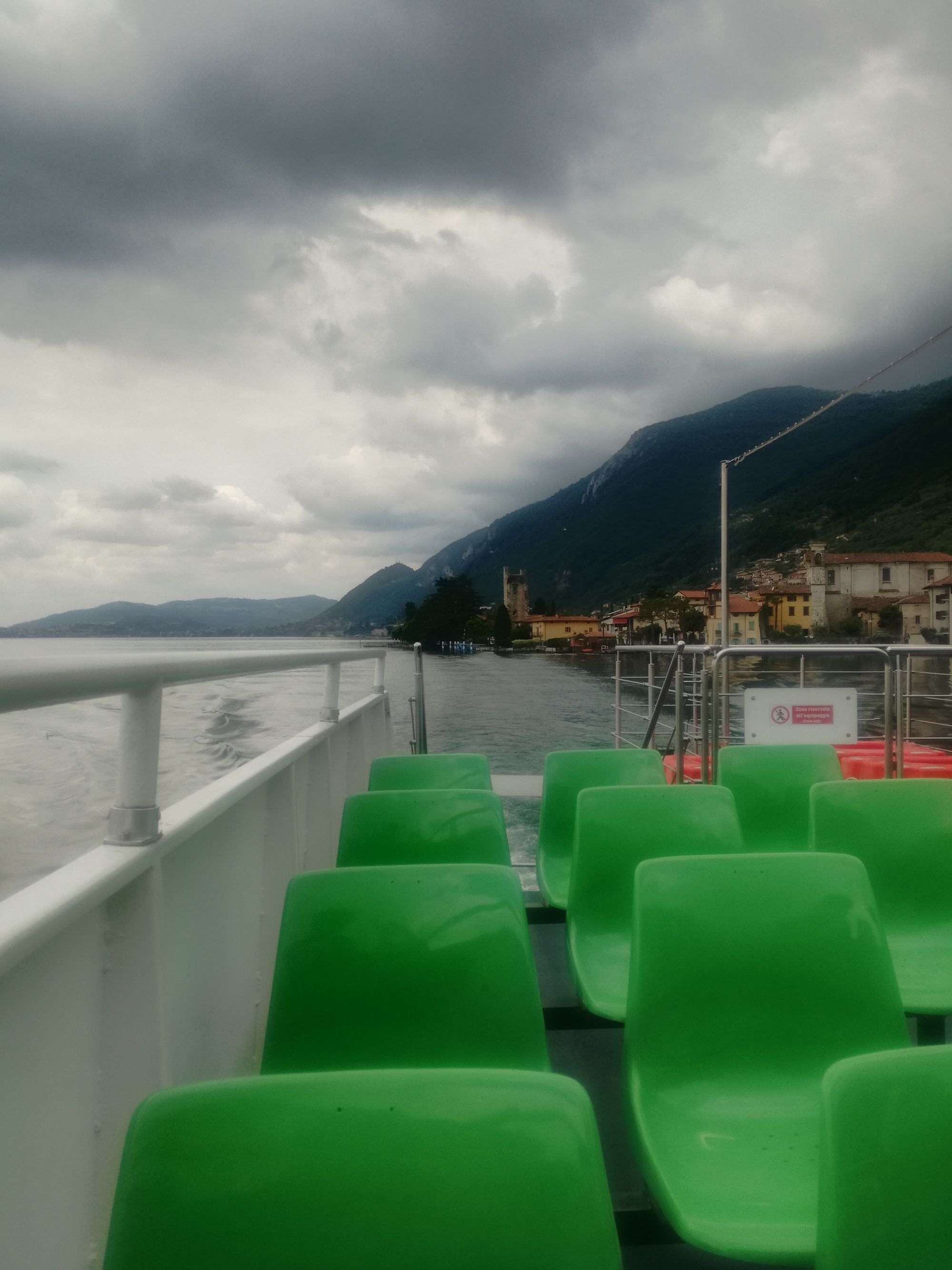 Grüne Plastikstühle auf der Fähre mit grauen Wolken am Himmel.