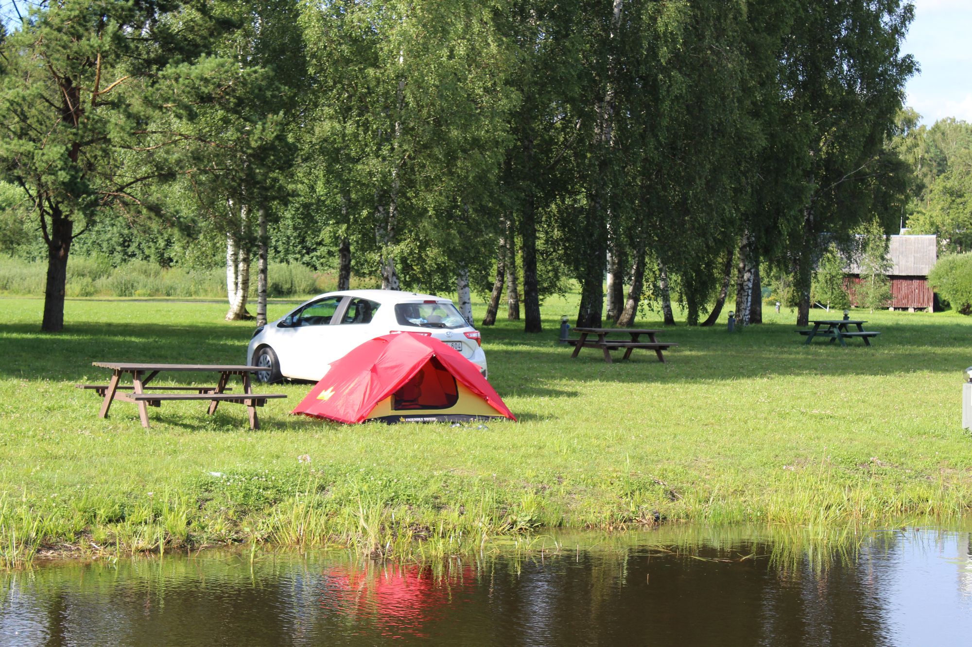 Zeltwiese mit Auto und Zelt direkt am Seeufer vom See Usma