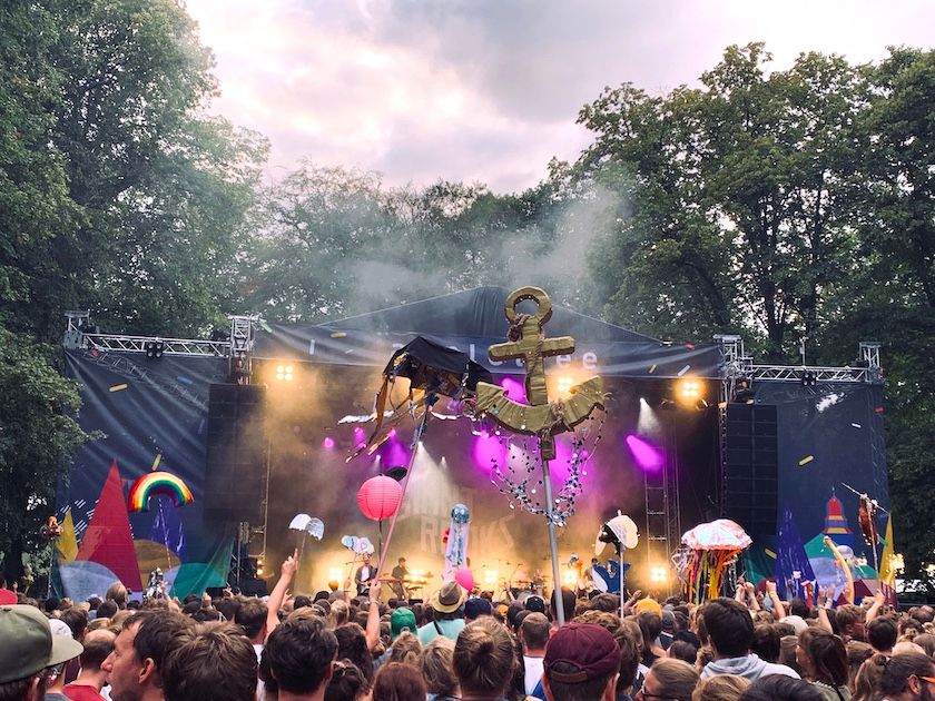 Blick auf Festivalbühne, über viele feiernde Menschen hinweg.
