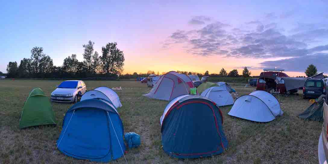 Eine Festivalwiese mit Zelten bei Sonnenaufgang.