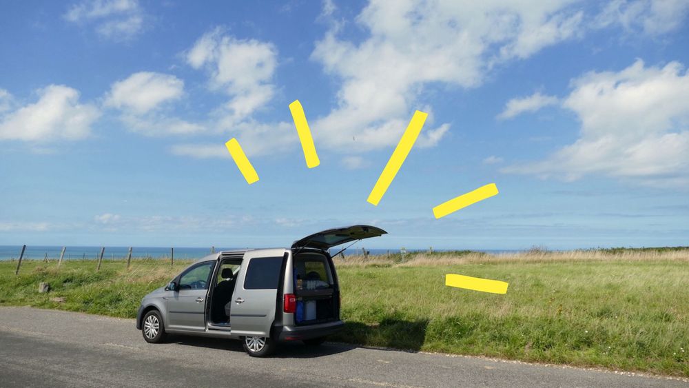 Minicamper steht an einem schönen Küstenweg. 