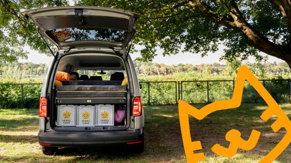 VW Caddy mit Campingmodulen auf einem Campingplatz.