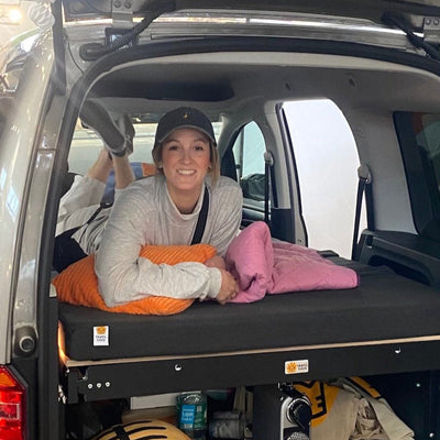 Trade fair visitor lies on the camping bed in the VW Caddy.
