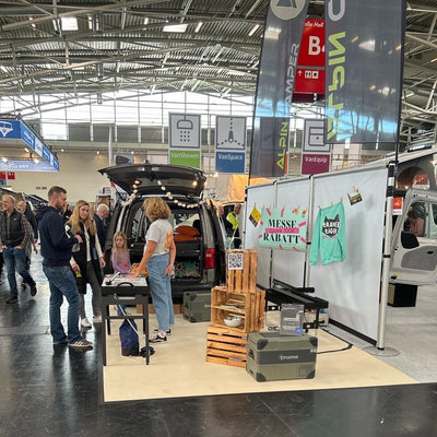 Exhibition stand at the free camping fair with visitors, VW Caddy and camping modules.